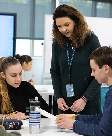 Female teacher leading a group of students at a table.